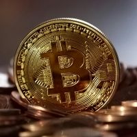 Moeda redonda de metal dourado com o simbolo do bitcoin no meio