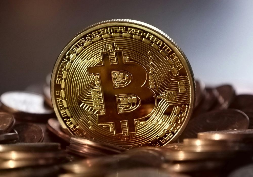 Bitcoin ultrapassa Alphabet e prata em valor de mercado e se torna o quinto ativo mais valioso do mundo em 2025. Entenda o que impulsionou essa alta!Moeda redonda de metal dourado com o simbolo do bitcoin no meio